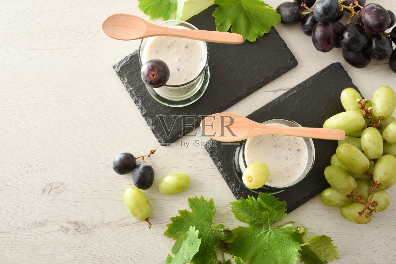 石板盘子上放着葡萄饮料，桌上放着葡萄串照片摄影图片