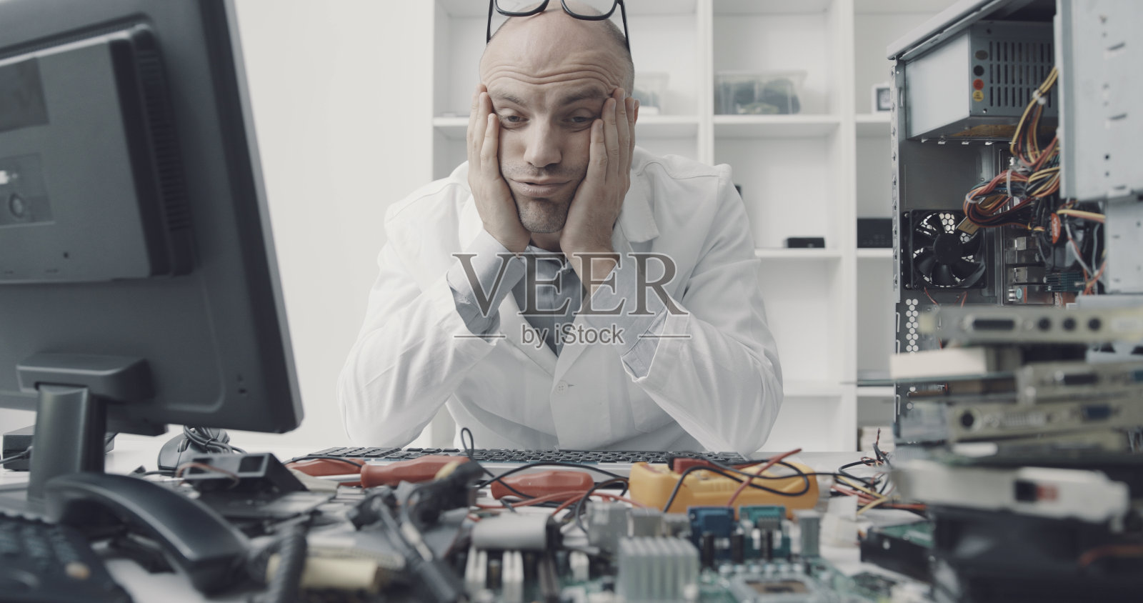 紧张沮丧的电脑维修技师坐在办公桌前照片摄影图片