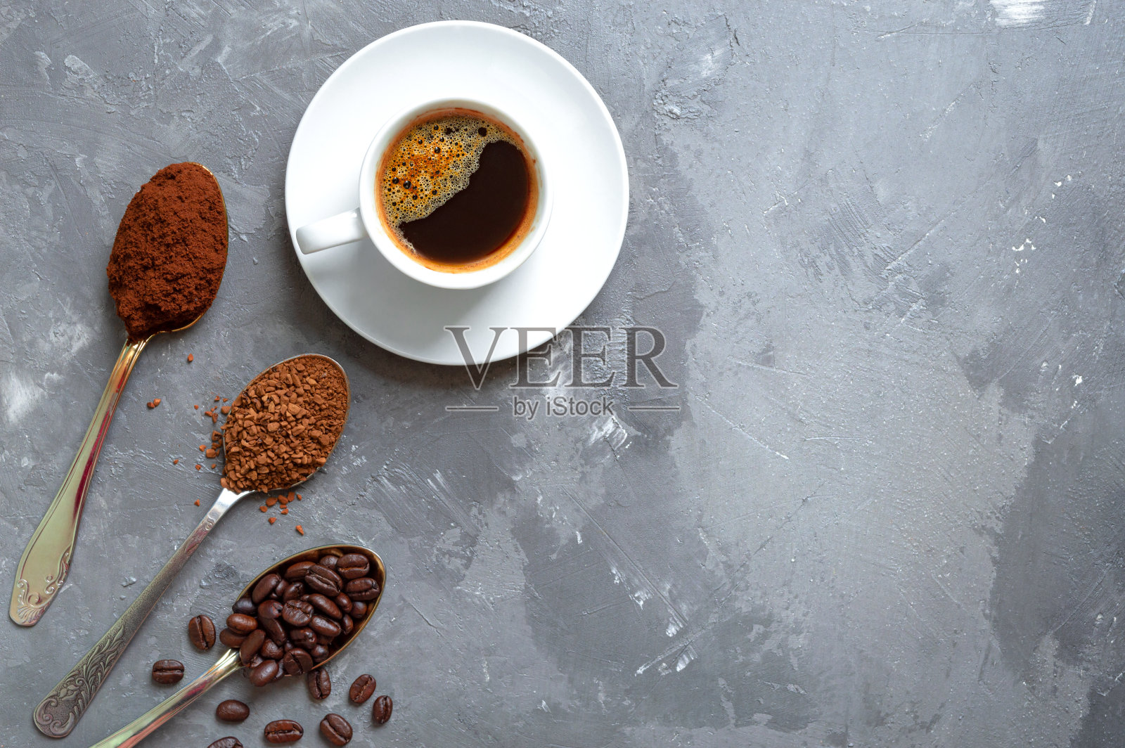 不同种类的咖啡。将咖啡豆、磨碎的速溶咖啡放在勺子里，再加一杯新鲜的意式浓缩咖啡。俯视图，复制空间。照片摄影图片