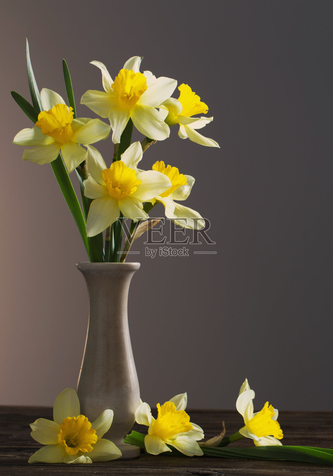 深色背景木桌上花瓶里的黄色水仙照片摄影图片