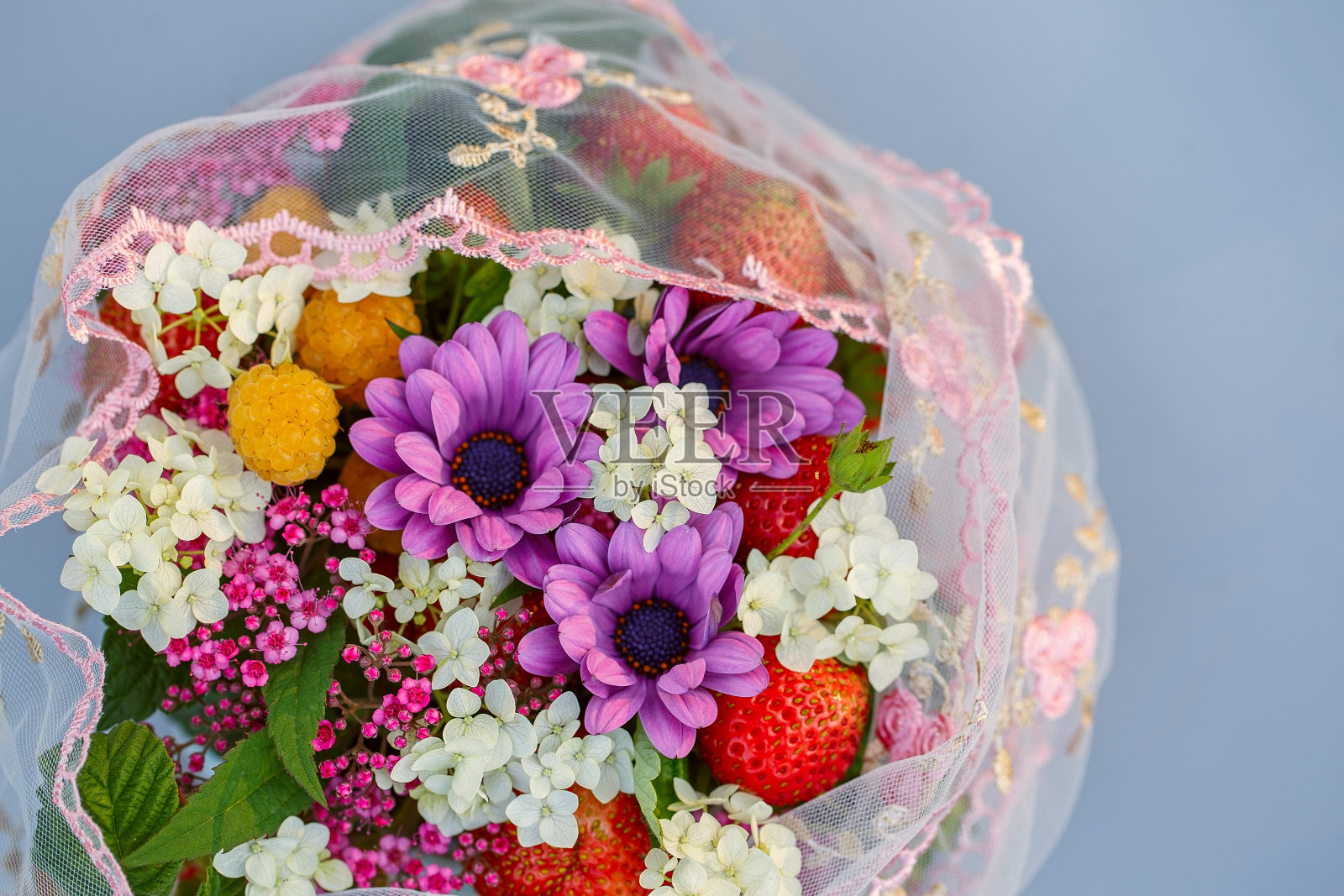 一束带花边的鲜花和草莓。紫色，白色和粉红色的鲜花特写照片摄影图片