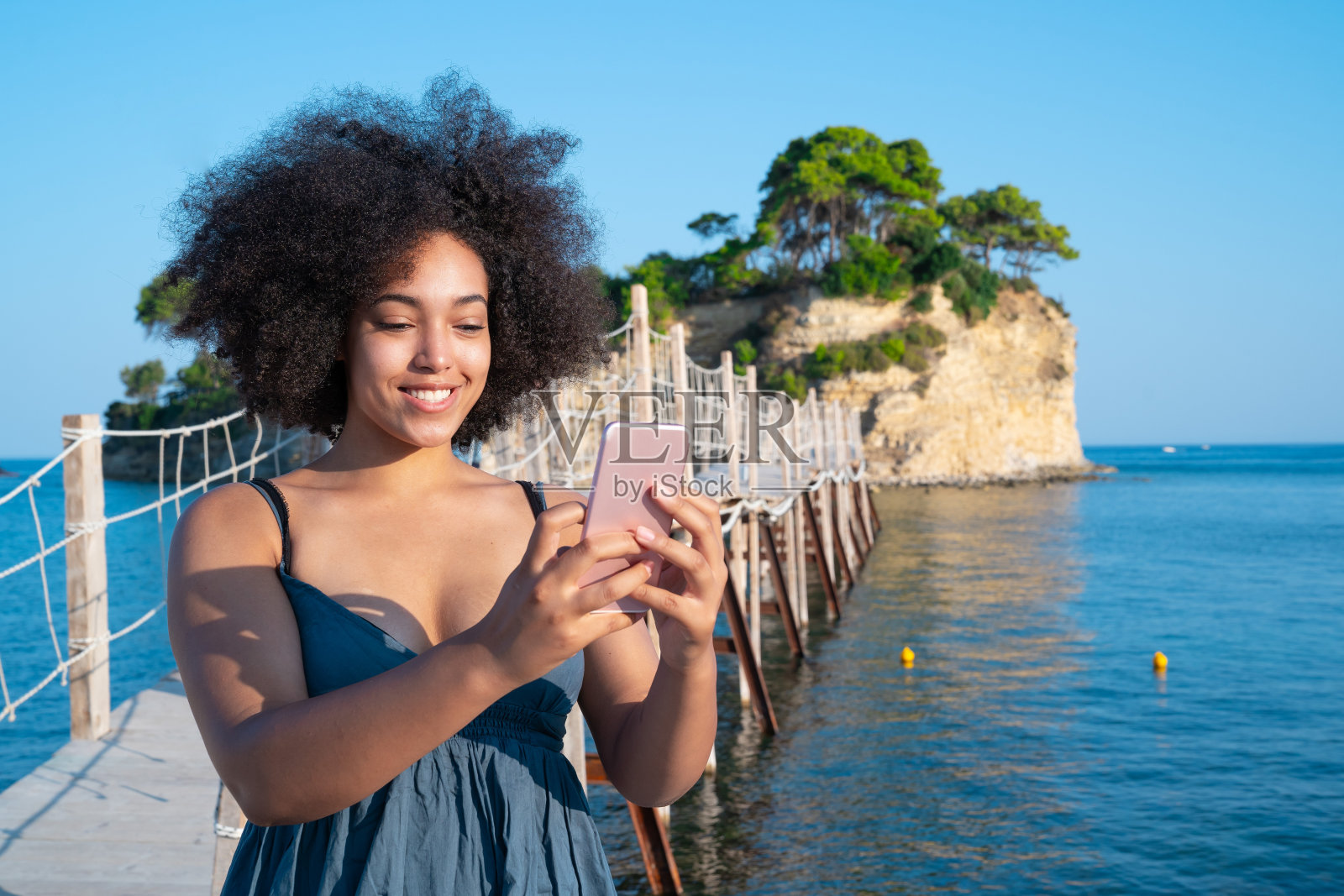 一名非洲妇女在希腊扎金索斯港使用智能手机照片摄影图片