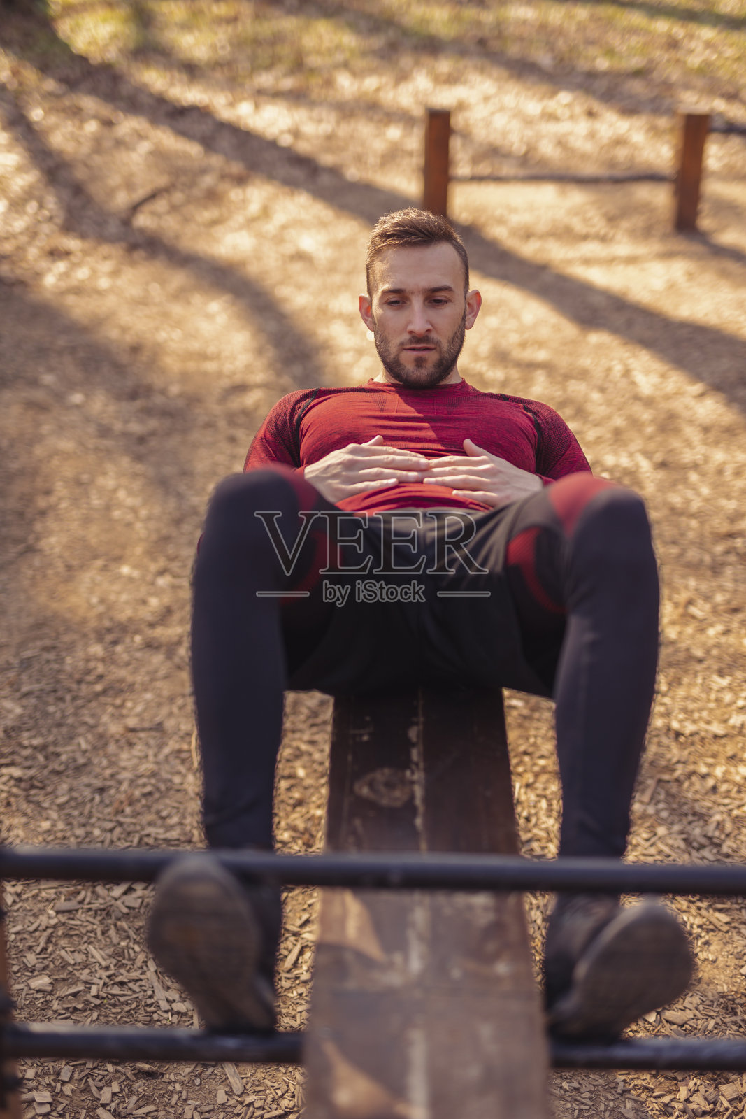 在街边健身公园里做仰卧起坐的男人照片摄影图片
