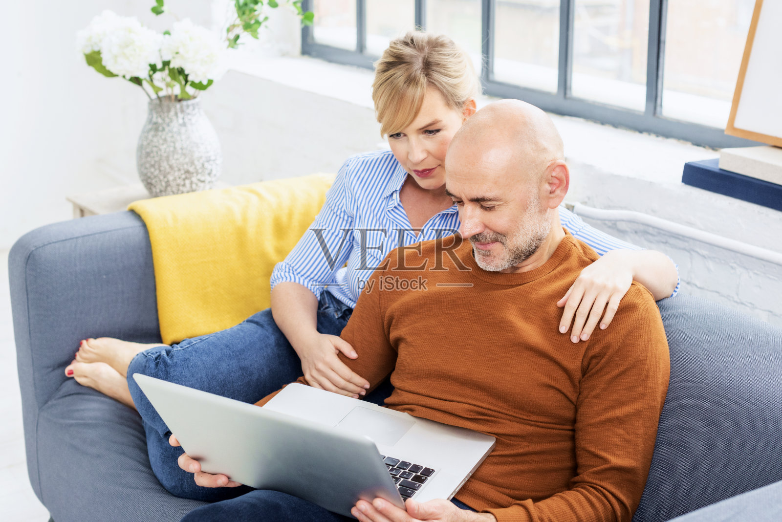 放松的夫妇坐在家里的沙发上使用笔记本电脑照片摄影图片