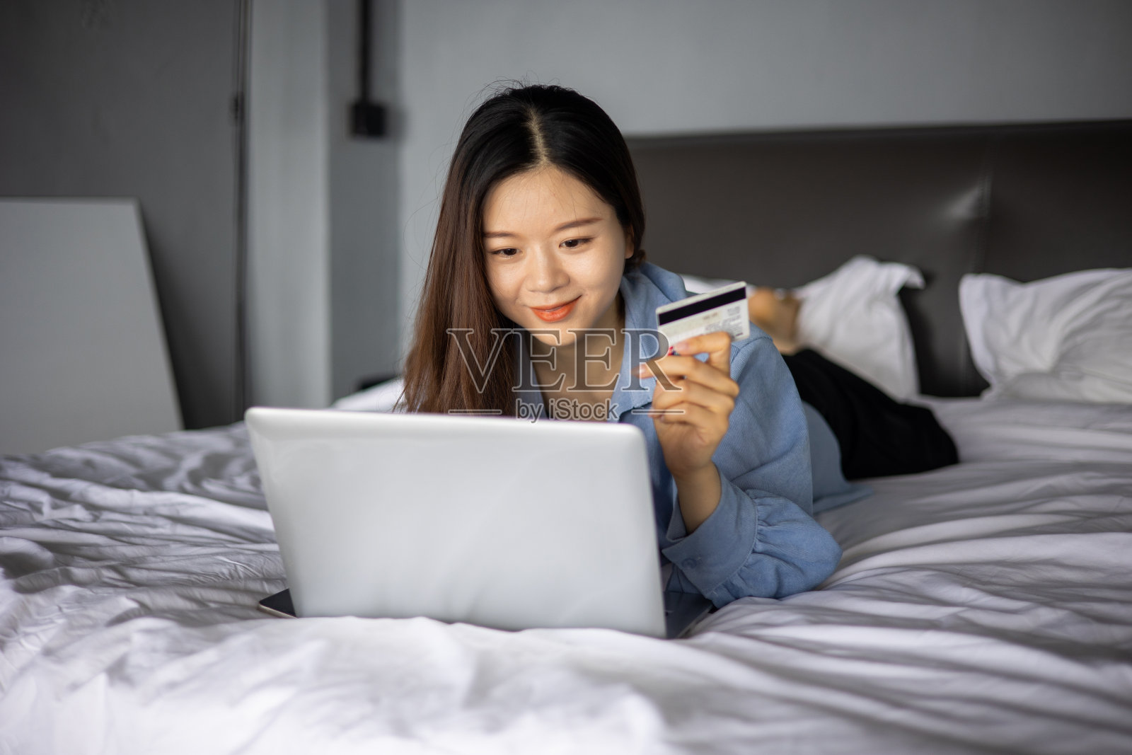 年轻女性躺在床上用笔记本电脑网购照片摄影图片