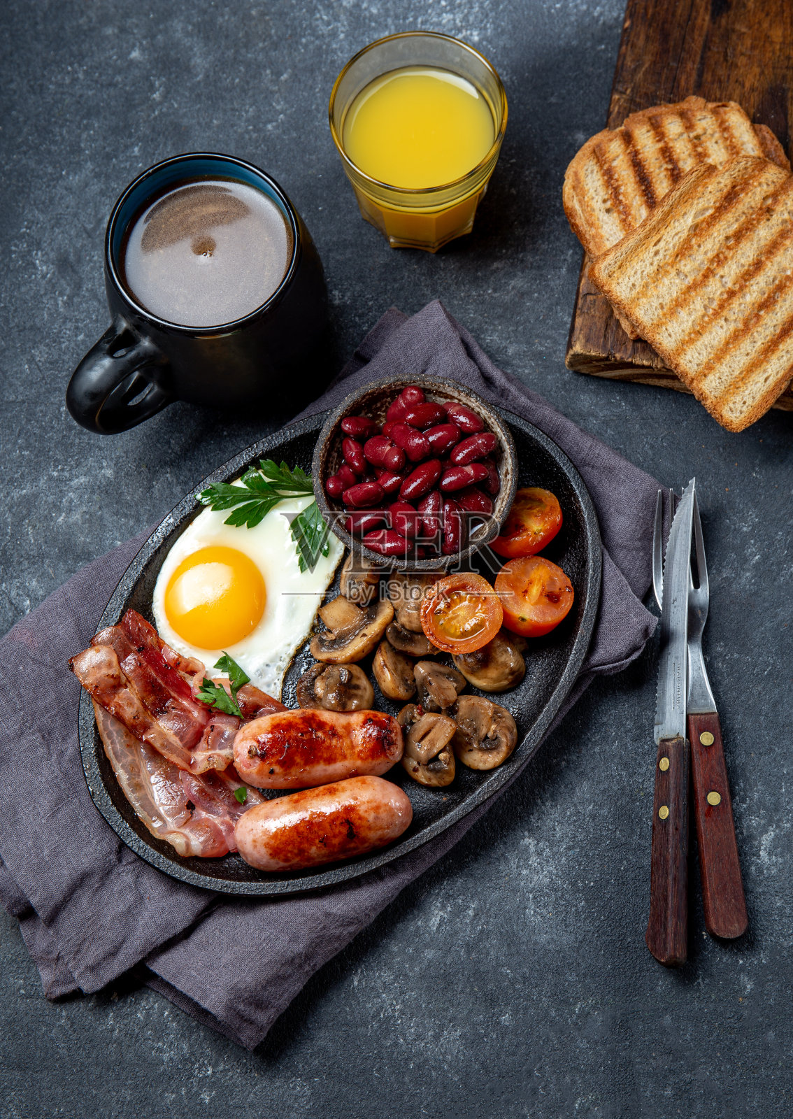 英式早餐，有煎蛋，培根，香肠，豆子，黑底烤面包照片摄影图片