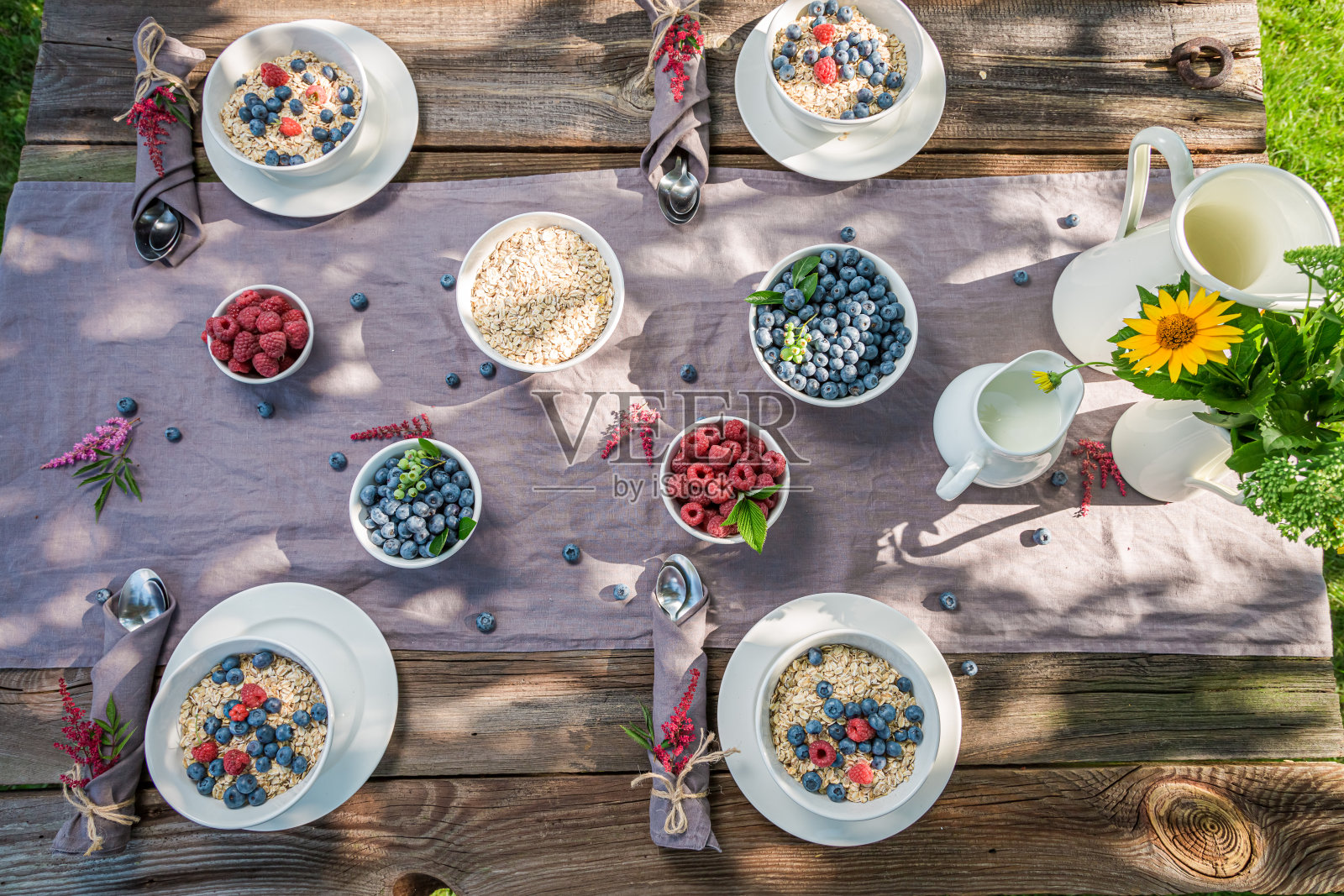 有浆果和牛奶的健康早餐。在阳光明媚的花园里吃饭。照片摄影图片