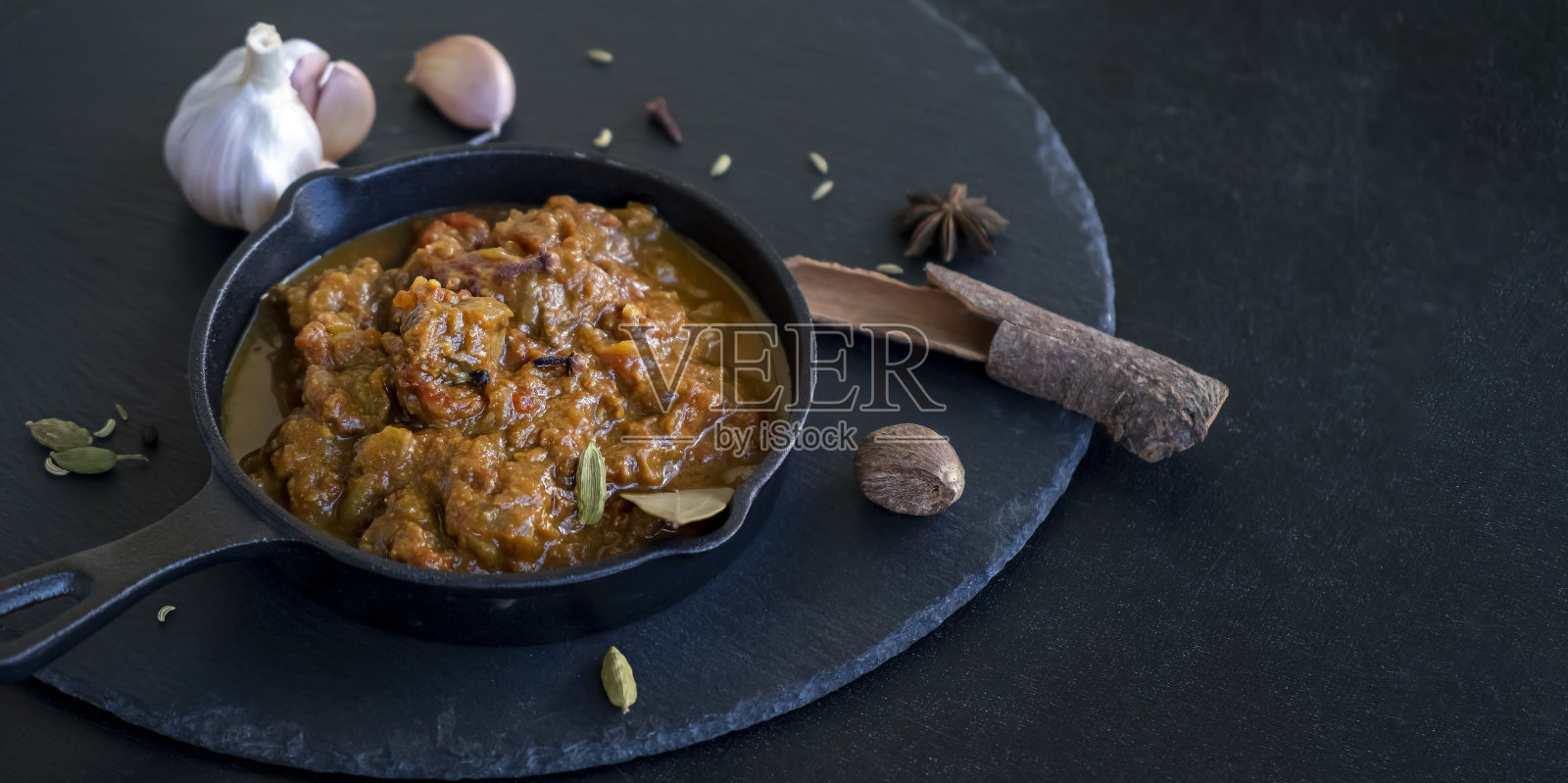 传统的印度咖喱牛肉是铁铸的。世界美食。黑色板岩的背景。横幅的尺寸。照片摄影图片