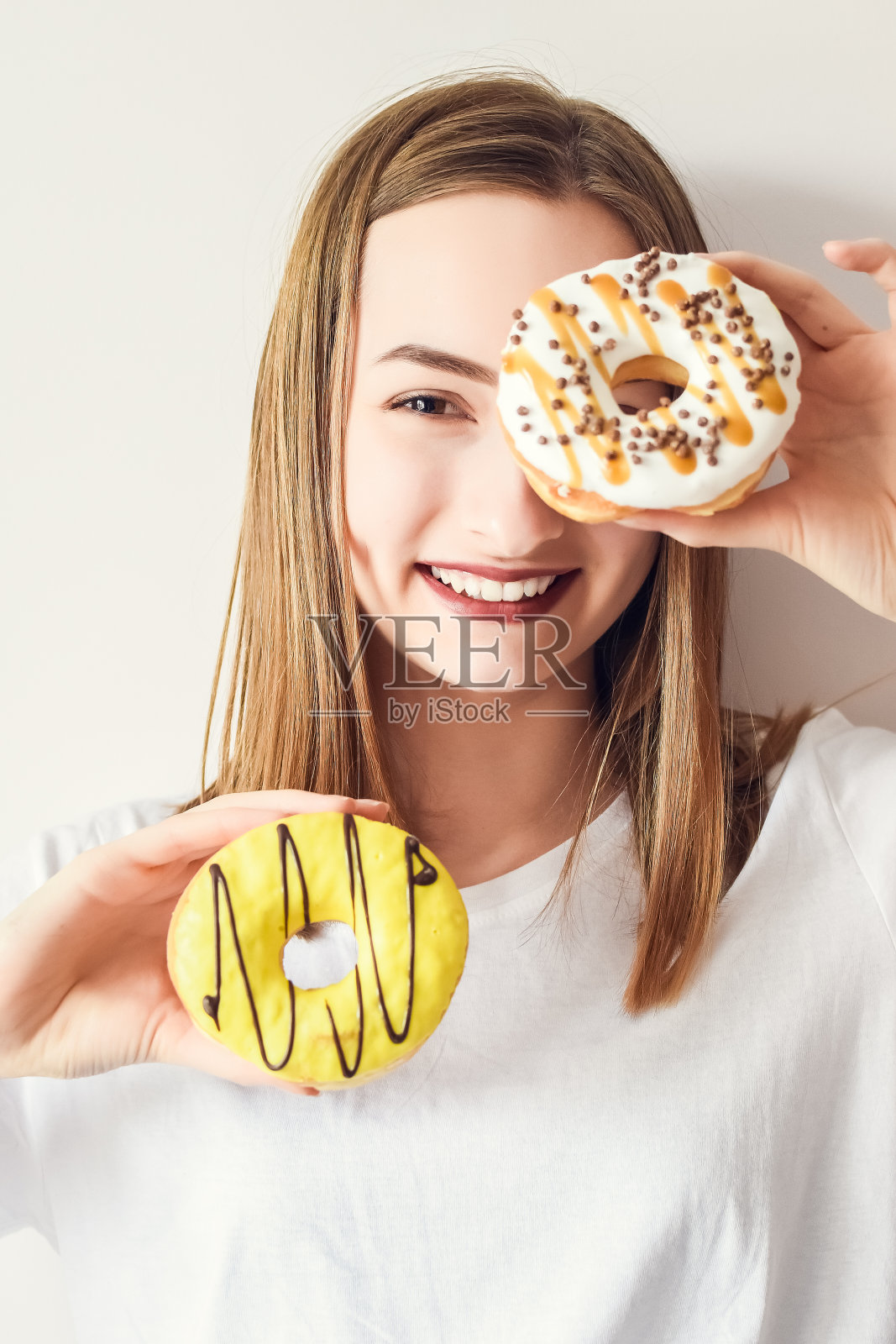 漂亮女孩拿着甜甜圈玩得很开心照片摄影图片