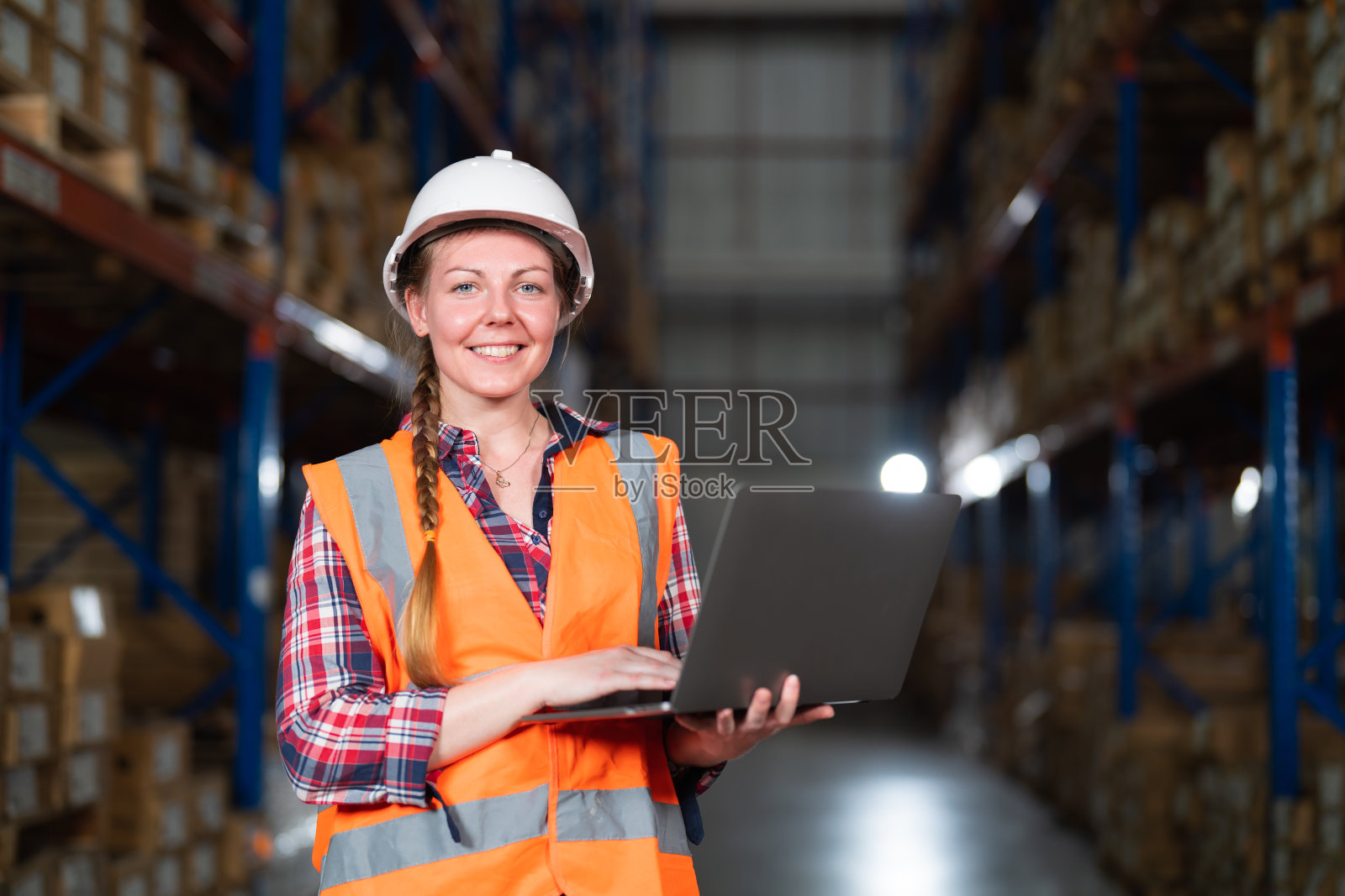 一名仓库工人站在大型配送中心的肖像。照片摄影图片