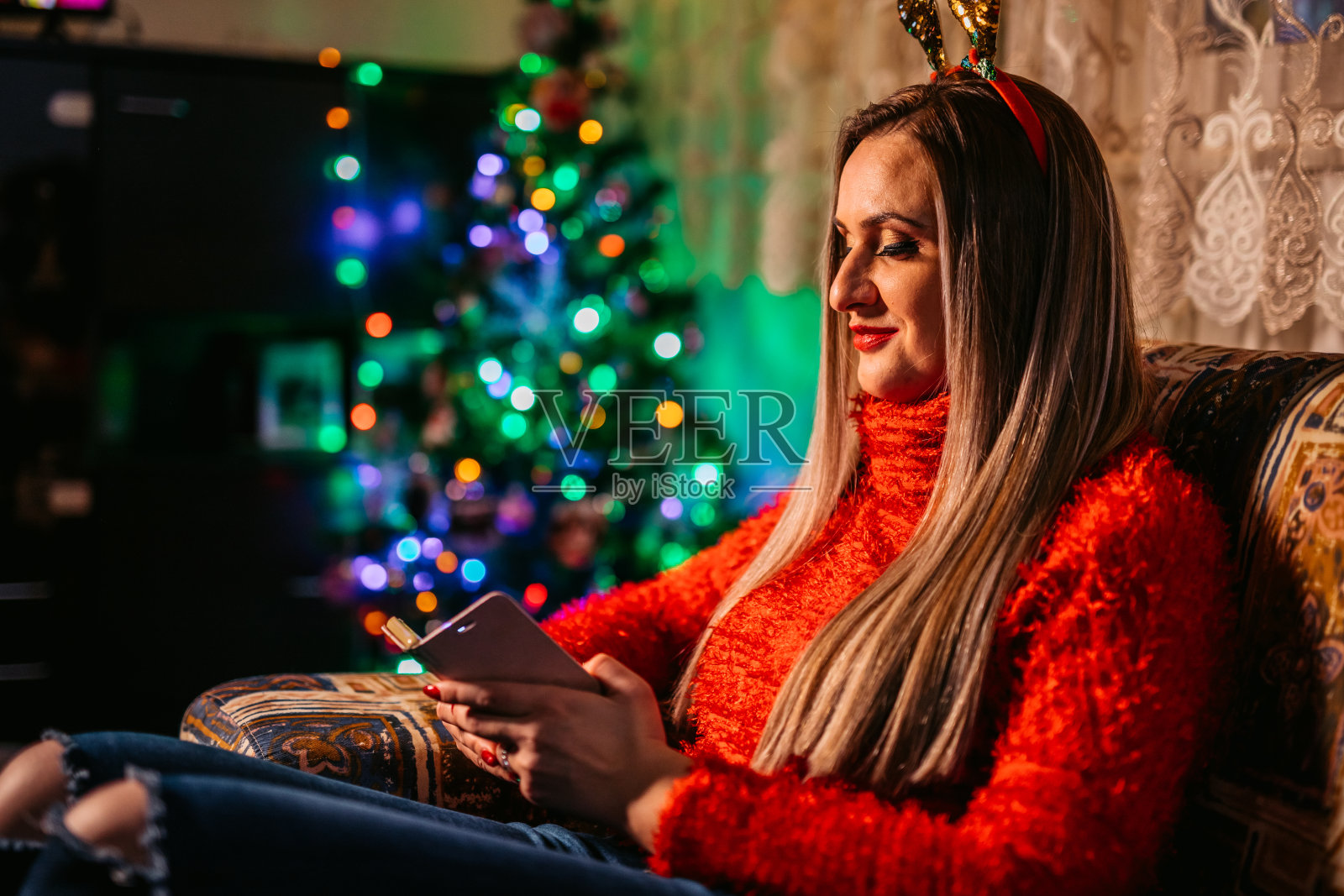 坐在圣诞树旁发短信的女人照片摄影图片