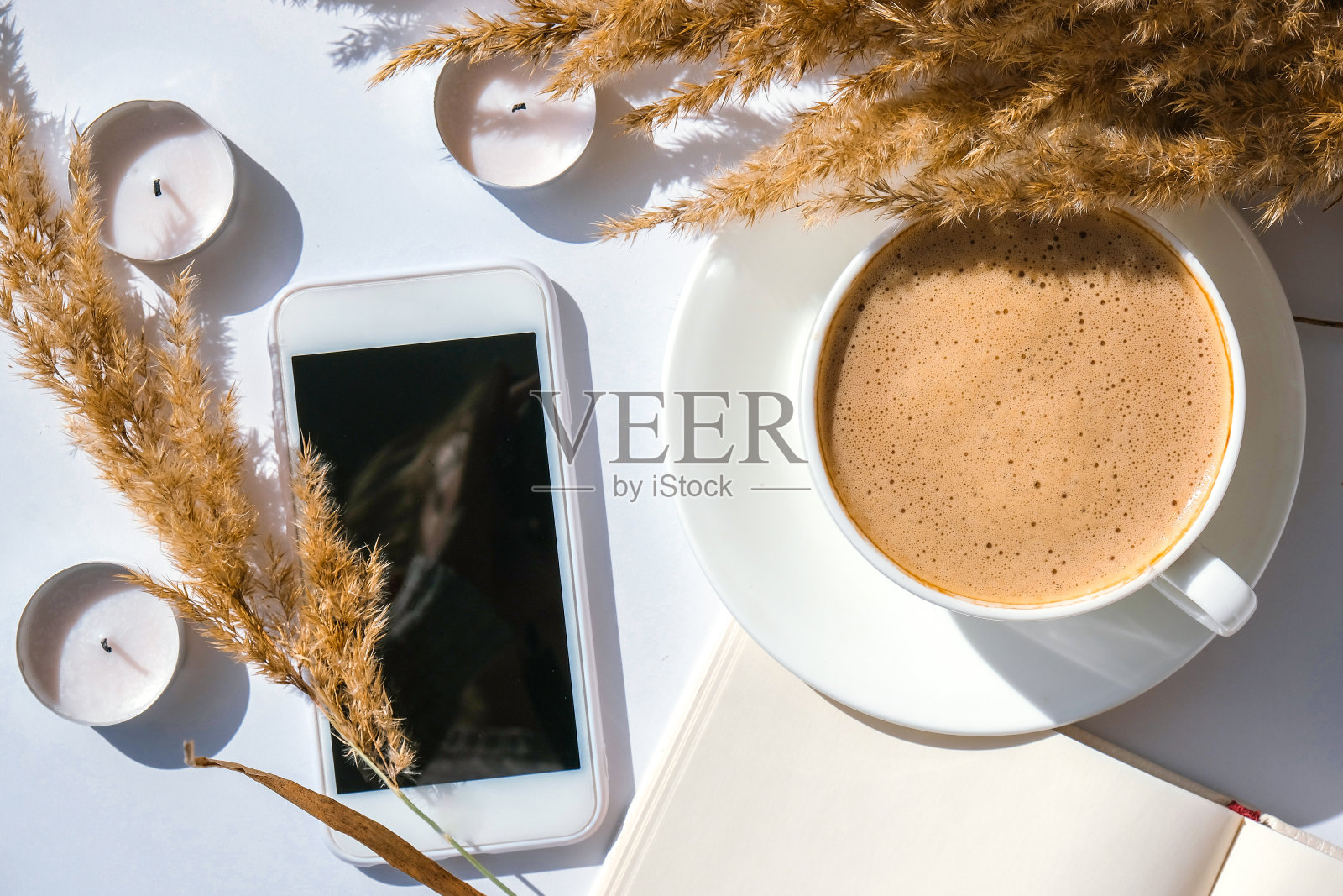 潘帕斯草原和白色的咖啡杯。黑屏手机。在家吃早餐时喝卡布奇诺。平的。墙纸。美学照片摄影图片