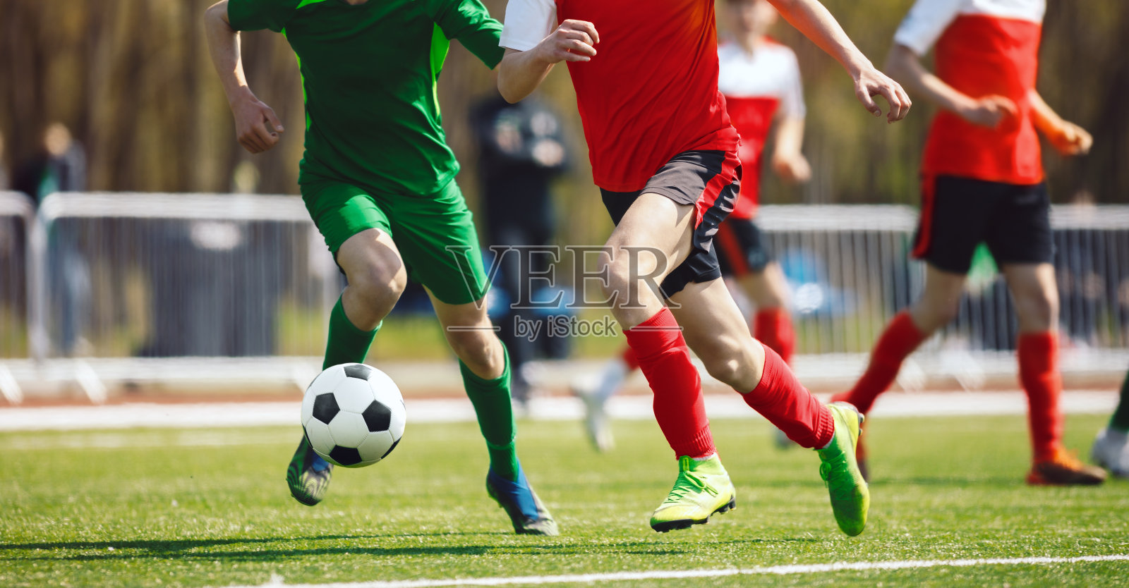 足球运动员在决斗中奔跑。成人足球运动员在比赛中。运动员在草地上踢足球照片摄影图片