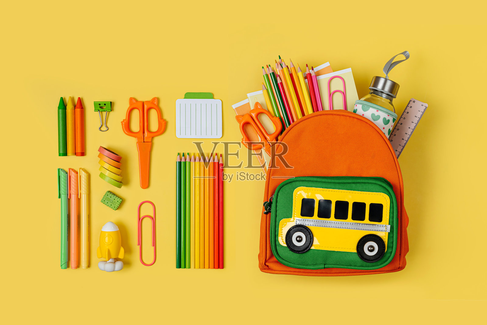 黄色背景的校车儿童双肩包。打开文具学校背包。小学或幼儿园。照片摄影图片