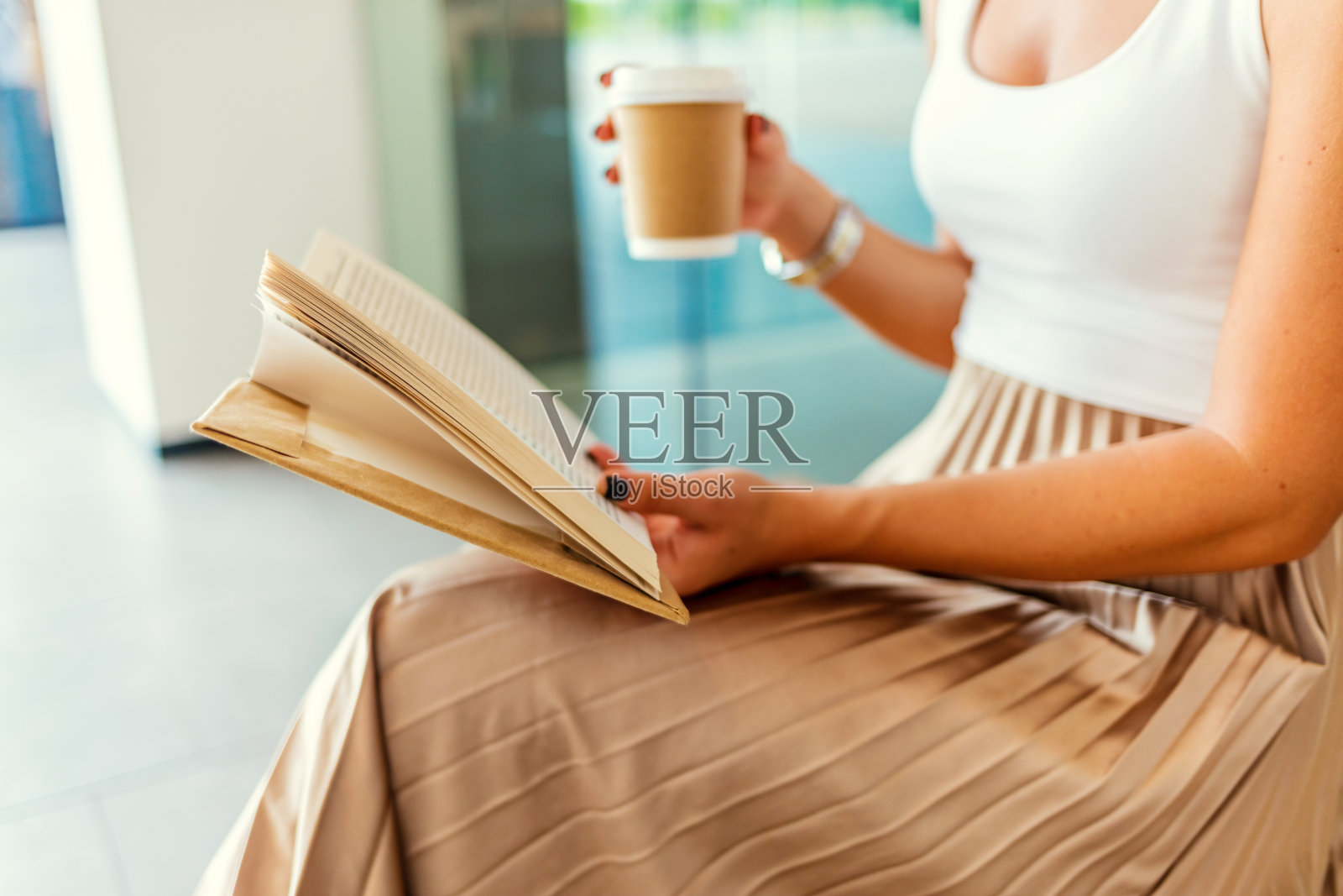 女人手里拿着书和咖啡。照片摄影图片