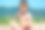 中午，一个穿着短裤的小男孩赤裸着上身坐在湖上的沙滩上。素材图片